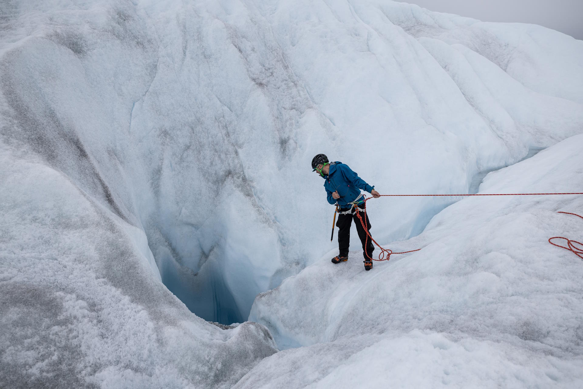 Matt peers into the depths of a moulin, assessing its worthiness for Cryoegg deployment. (Photo: Scott Crady)