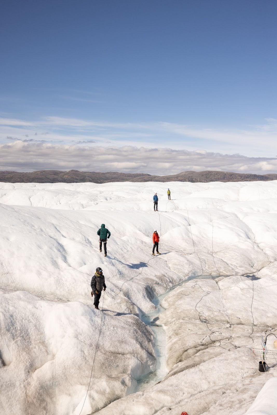 Team scenes. Typically we worked in small groups across the glacier, but sometimes we all came together for a big job. In this case we are lowering 300 meters of pressure transducer cable into the glacier. (Photo: Scott Crady)